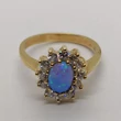 Gyönyörű ovális kék opál arany gyűrű, amelyet karmos foglalatú cirkon kövek kereteznek