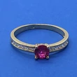Középen 4 karomba foglalt kerek rubin színű, két oldalt fehér cirkon kővel díszített arany gyűrű