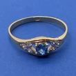 Klasszikus formájú középen 4 karomba foglalt kék topáz színű és két oldalt fehér cirkon kővel díszített arany gyűrű