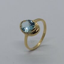 Ovális formájú középen  kék topáz szélén cirkon kővel díszített arany gyűrű