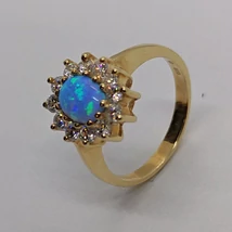 Gyönyörű ovális kék opál arany gyűrű, amelyet karmos foglalatú cirkon kövek kereteznek