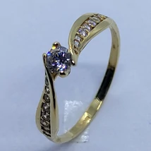 Középen 4 karomba foglalt kerek gyémánt csiszolású, két oldalt fehér cirkon sor kövekkel díszített arany eljegyzési gyűrű