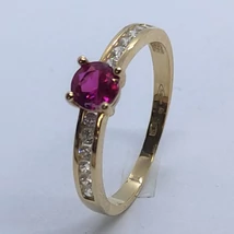 Középen 4 karomba foglalt kerek rubin színű, két oldalt fehér cirkon kővel díszített arany gyűrű