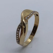 Végtelen jelre emlékezetető fejrészű, két oldalt ellentétes irányban hullám vonalasan cirkon kővel kirakott arany gyűrű