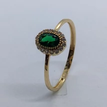 Középen zöld színű ovális cirkon kővel és apró fehér kövekkel keretezett arany gyűrű