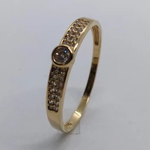 Karika gyűrűre emlékeztető középen buttonos foglalatú, két oldalt apró fehér cirkon kövekkel díszített arany gyűrű