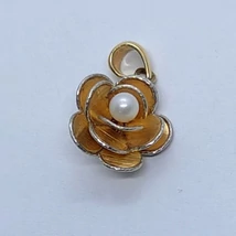 Nagyon különleges formában készített rózsa arany medál, melyet középen egy fehér gyönggyel, a szirmok széleit csiszolt fehér arany szegéllyel díszítettek