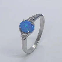 4 karomba foglalt, ovális kék opálkővel, két oldalt háromszög alakban fehér cirkon kövekkel díszített ezüst gyűrű