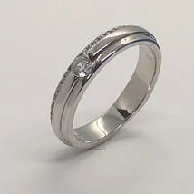 Sín részbe süllyesztett viszonylag széles fazonú, egyikfelén fehée cirkon sorkővel díszített euüst eljegyzési gyűrű