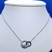 Anker lánc közé beépített két karika, melyből az egyik dupla cirkon sorkővel kirakott bal oldalon, 6 mm-es édesvizi gyönggyel díszített ezüst medál