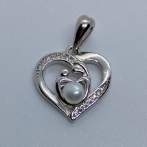 Szív medál amely anya gyermekét körbe fogja, és két szemben lévő oldal apró cirkon kővel kirakva mely tenyésztett gyöngyel is ellátott  ezüst medál
